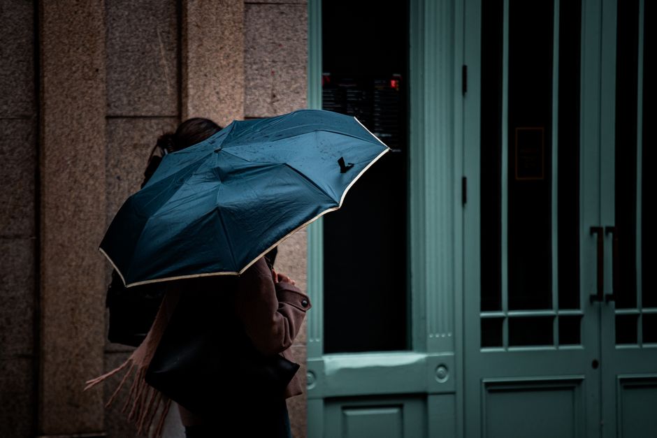 A moody city scene with a person holding an umbrella, captured in an urban environment on a rainy day