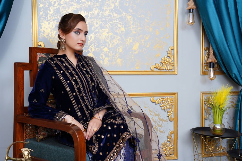 A woman elegantly dressed in traditional blue attire posing in an ornately decorated room