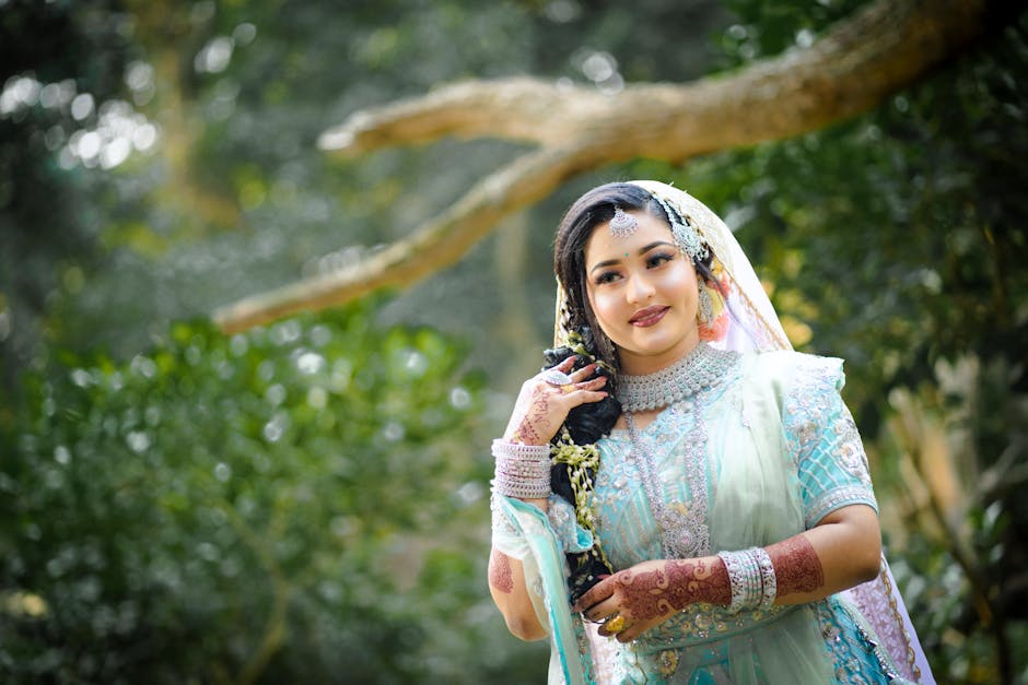Elegant portrait of a bride in ornate traditional attire set against a lush outdoor backdrop.
