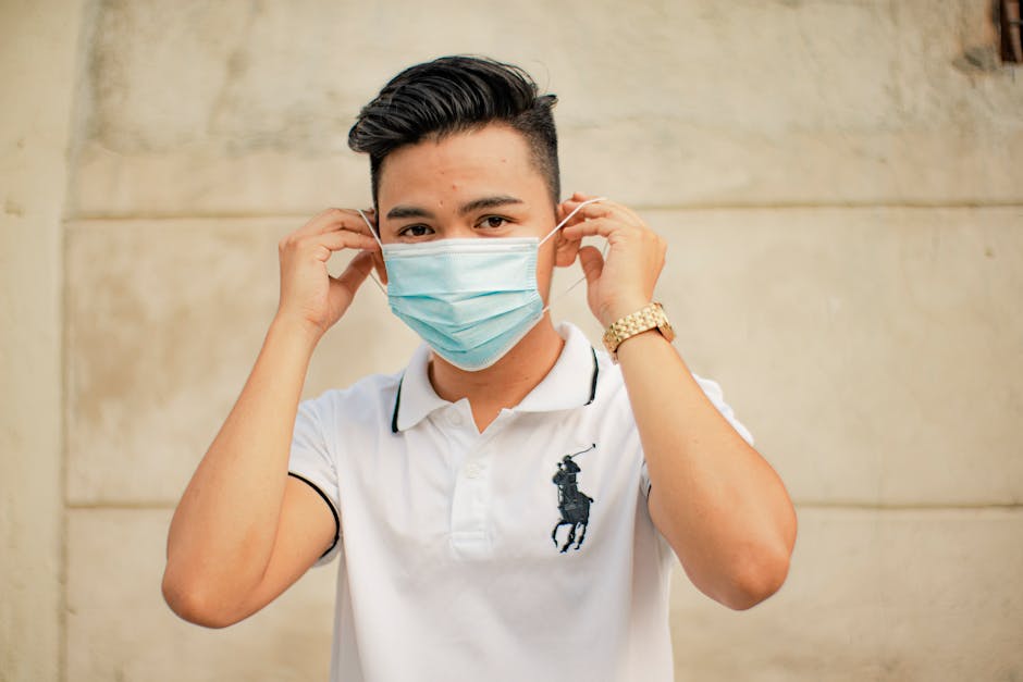 Portrait of a young man adjusting his face mask outdoors for protection and safety.
