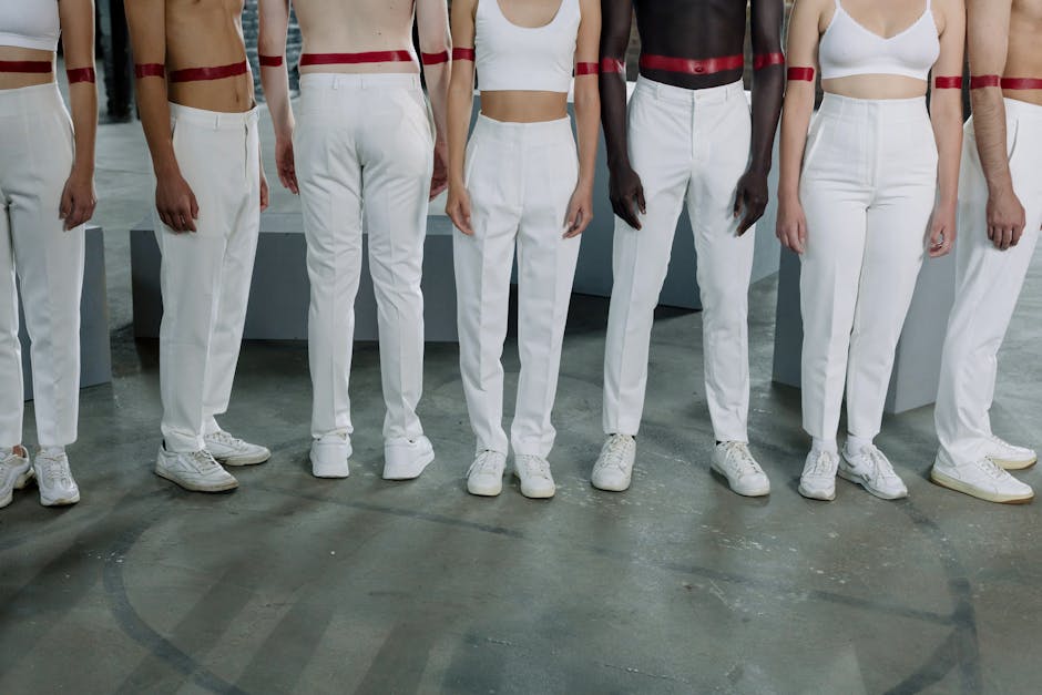 A diverse group of people standing in white outfits with red armbands, symbolizing unity.