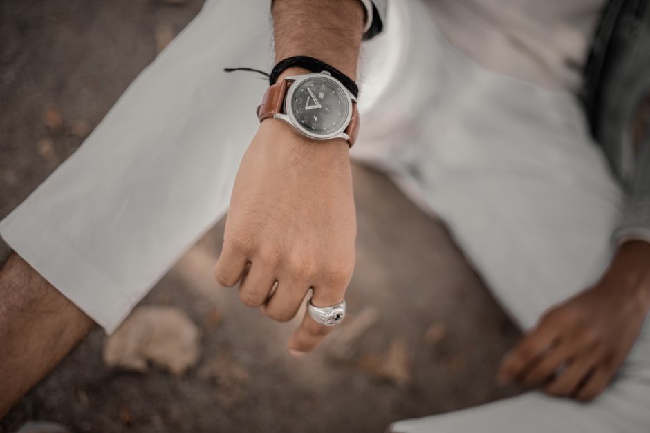 A close-up of a man's hand wearing a stylish wristwatch and a silver ring, showcasing modern fashion.
