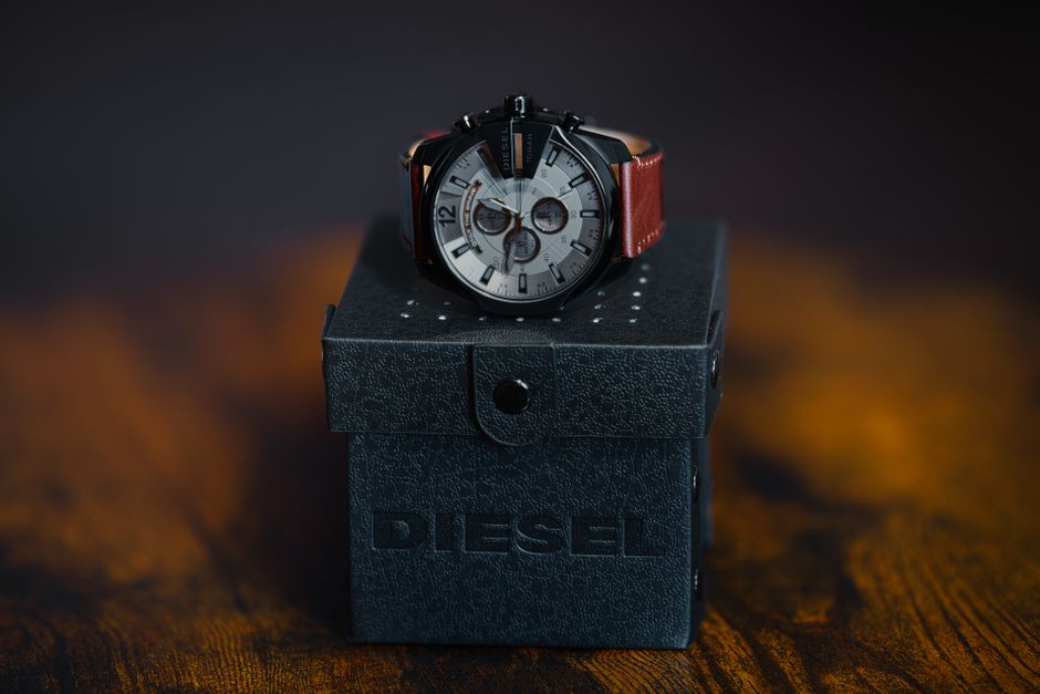 Elegant Diesel watch with red leather strap on branded box, moody backdrop.