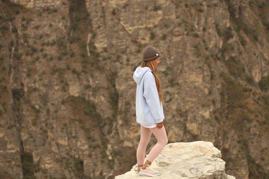 A woman standing on a rocky cliff edge, overlooking a canyon, embodying adventure and exploration.