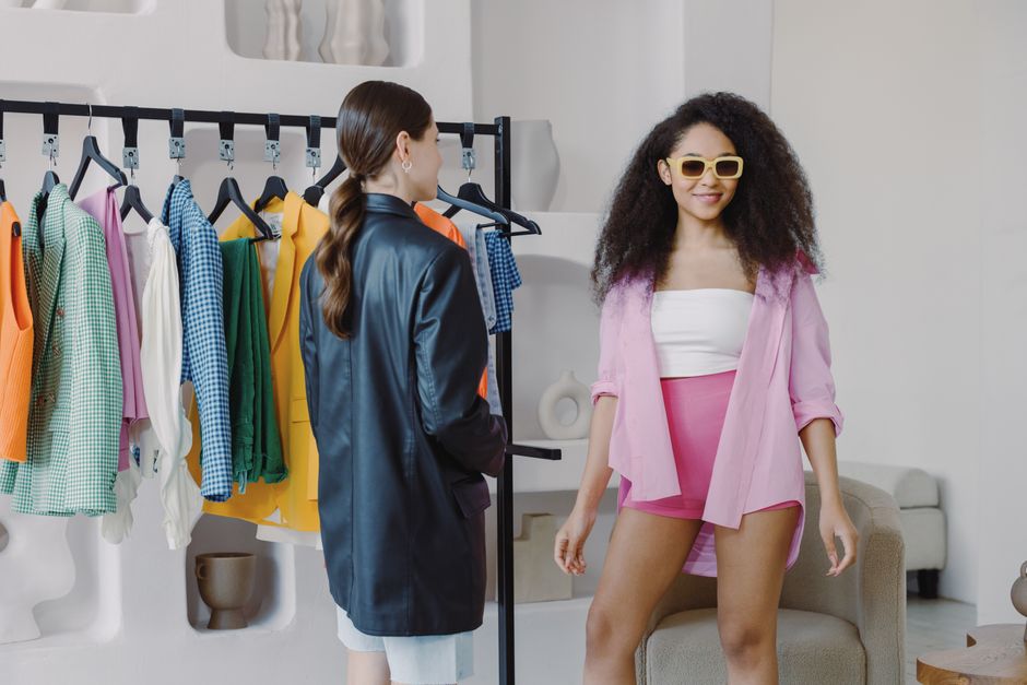 Two women exploring colorful outfits on a rack in a stylish indoor setting.