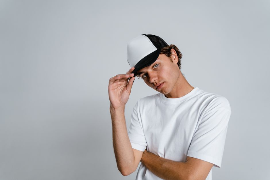 Young man wearing a cap and white t-shirt against a plain background.