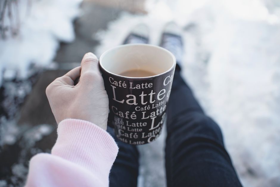 A person enjoying a warm café latte in a winter setting, creating a cozy vibe.