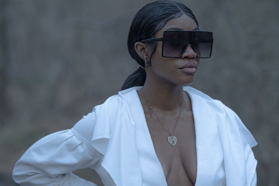 Stylish woman outdoors wearing oversized sunglasses and a white dress.