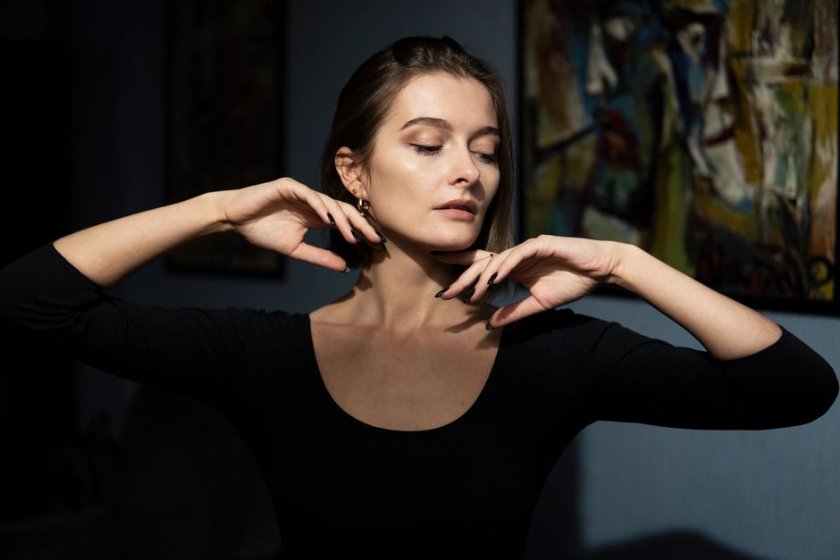 Intimate low-light portrait of a ballerina posing gracefully indoors with artistic background