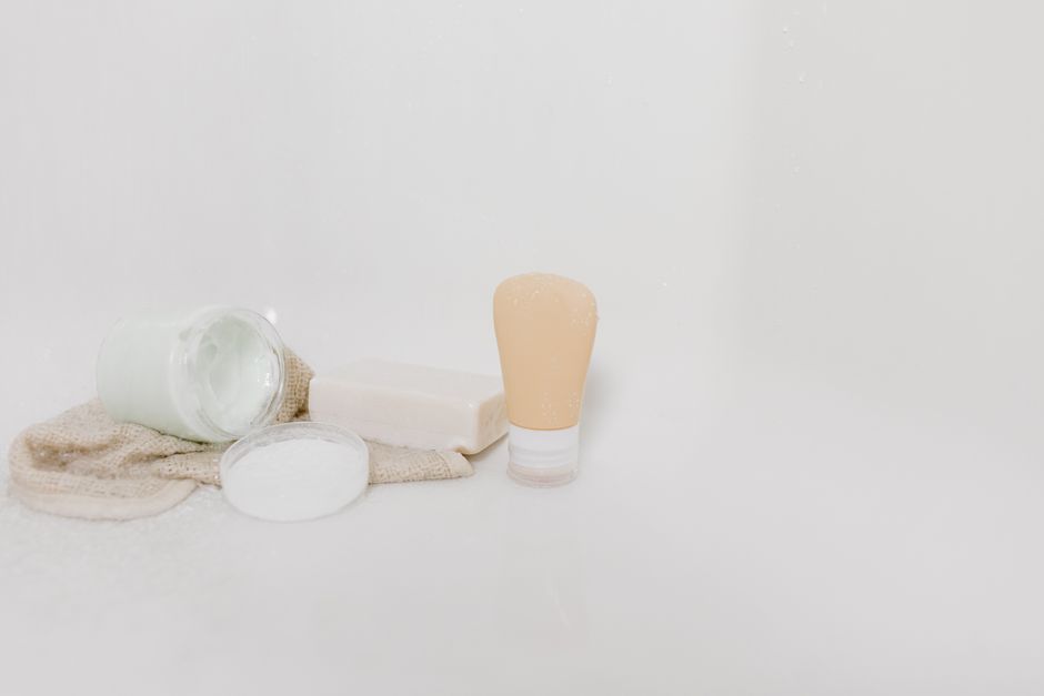 Minimalist setup of skincare products including cream, soap, and lotion on a white surface for beauty and self