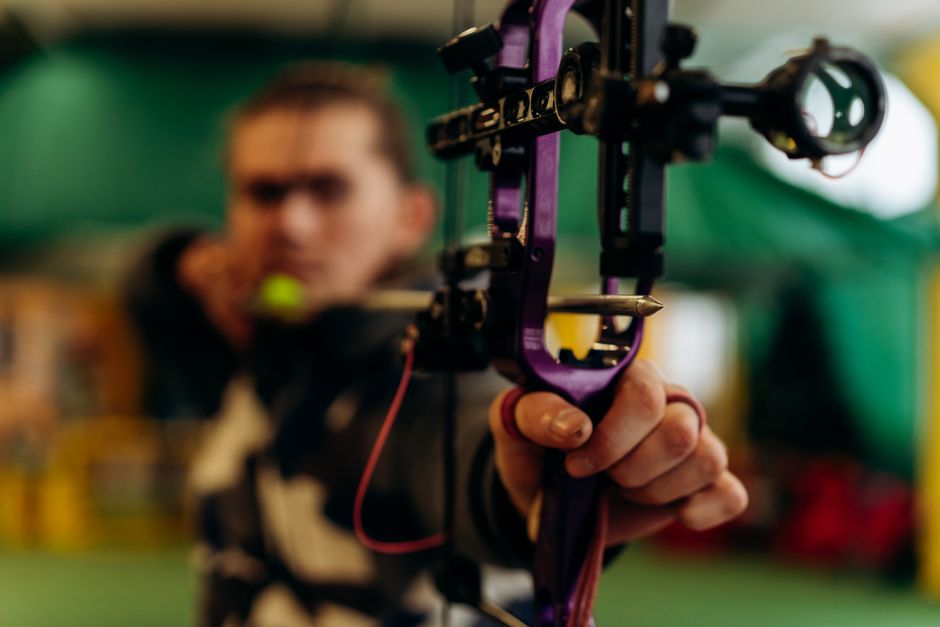 Focused man aiming a crossbow during indoor archery training.