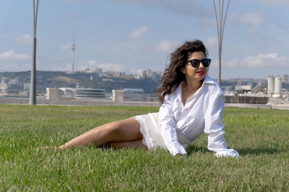 Outdoor portrait of a woman relaxing on grass in Baku with city skyline