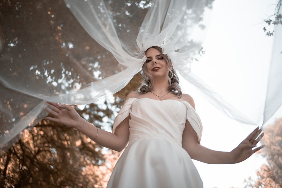 Ethereal portrait of a bride outdoors, draped in a flowing veil.