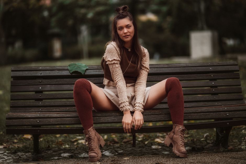Portrait of a fashionable woman sitting on a bench in a Lisbon park during autumn