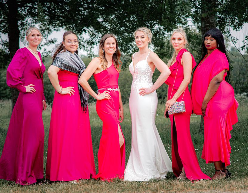 A diverse group of women celebrating in elegant attire featuring a bride in white and bridesmaids in vibrant pink dresses.
