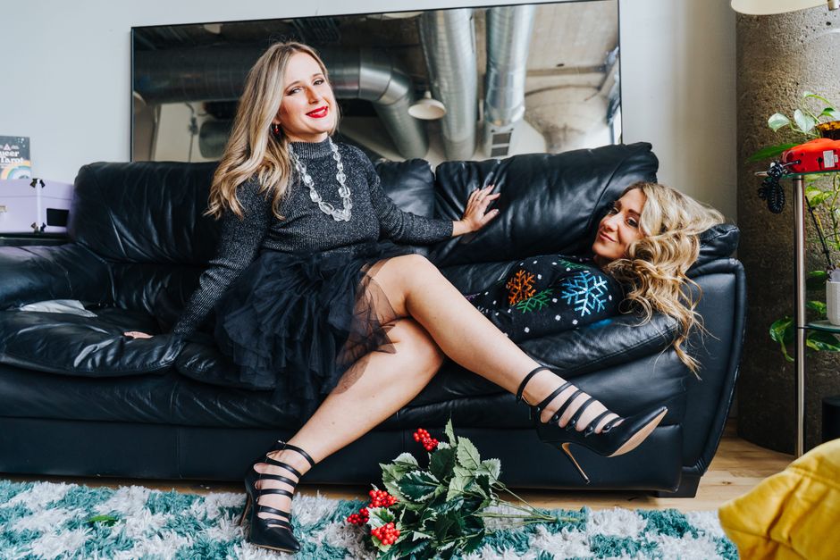 Friends enjoying a festive indoor holiday gathering, lounging on a sofa with cheerful decor.