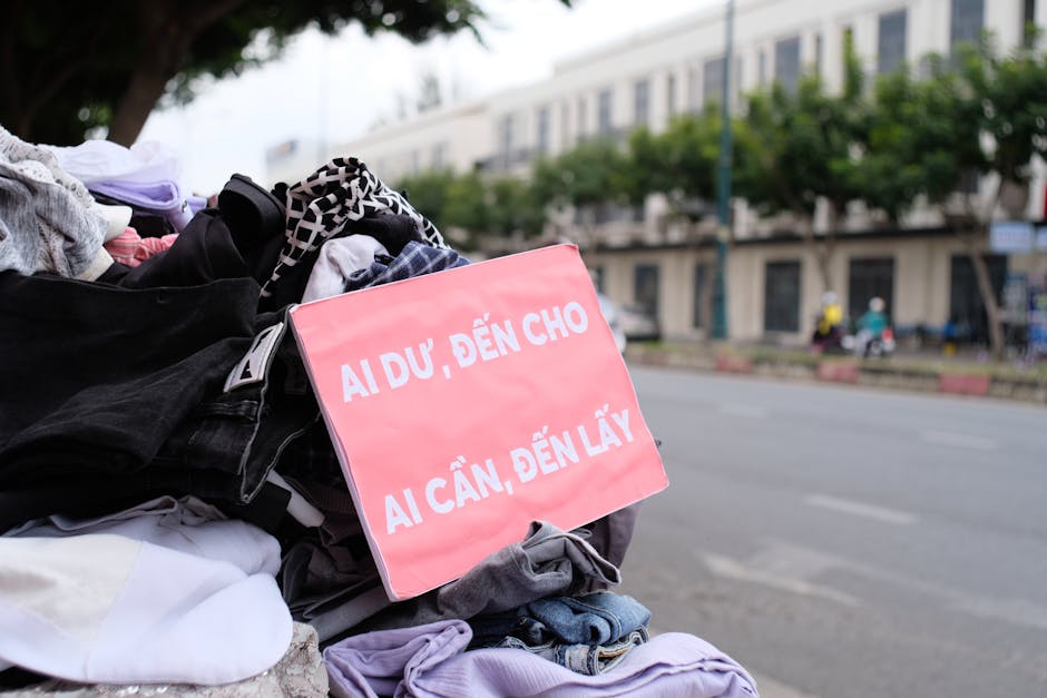 Clothes donation on city street with sign offering free items to those in need.