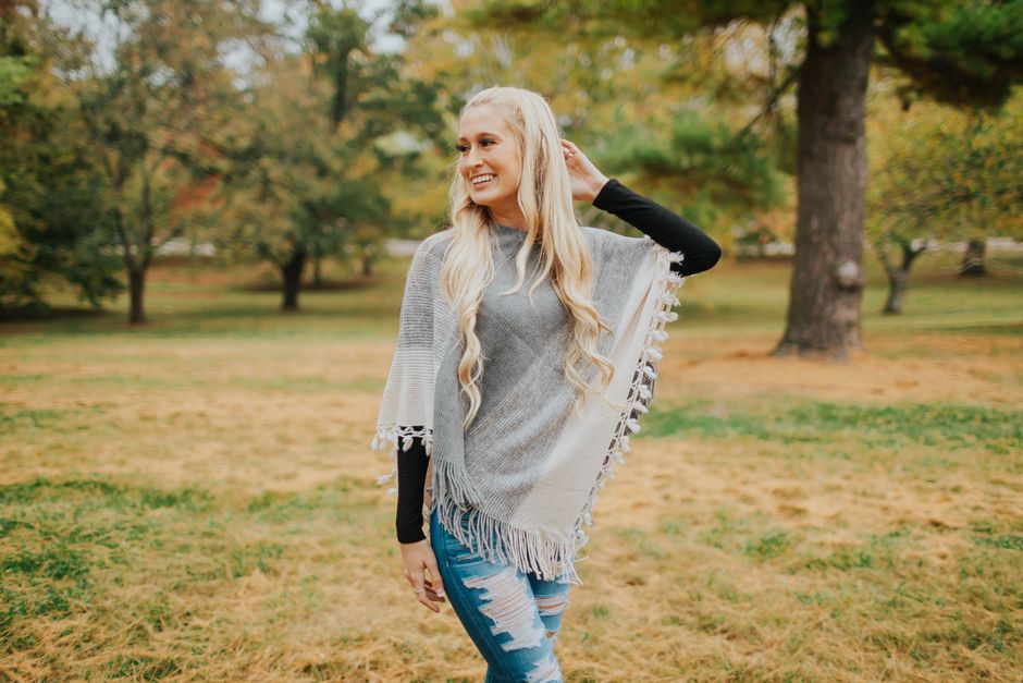Smiling blonde woman in a poncho enjoying a sunny day at the park