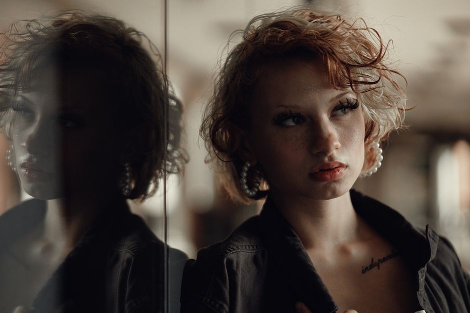 Artistic portrait of a freckled woman gazing at her reflection, indoors in Orlando, Florida.