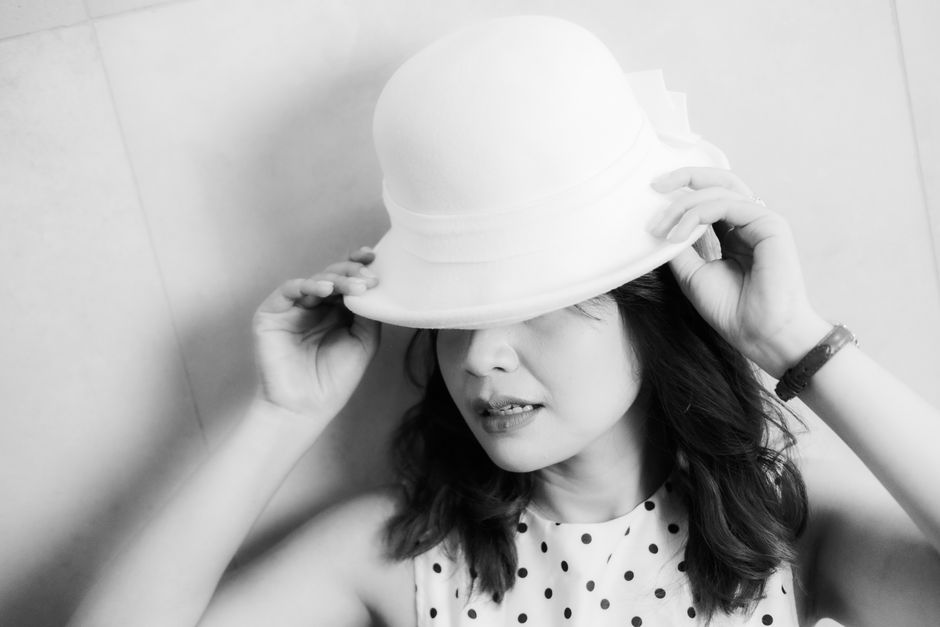 Stylish monochrome portrait of a woman adjusting her hat, creating a chic and elegant look