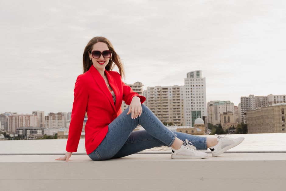 Stylish woman in red blazer posing against Baku skyline. Urban fashion and lifestyle