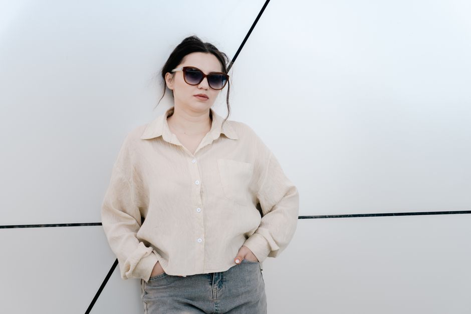 Trendy woman in sunglasses leaning against a geometric wall, showcasing fashion and confidence