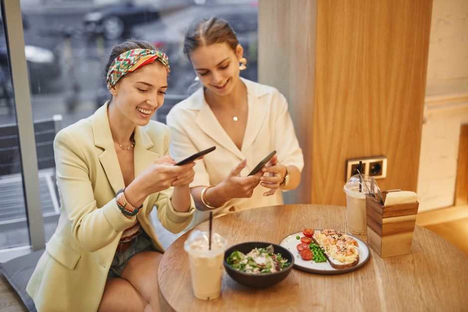 Two women enjoying drinks and snacks in a café, sharing moments and smiles