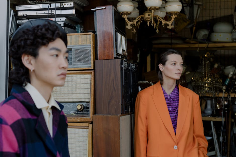 Two stylish individuals in a vintage store exhibit modern fashion against a backdrop of retro items.