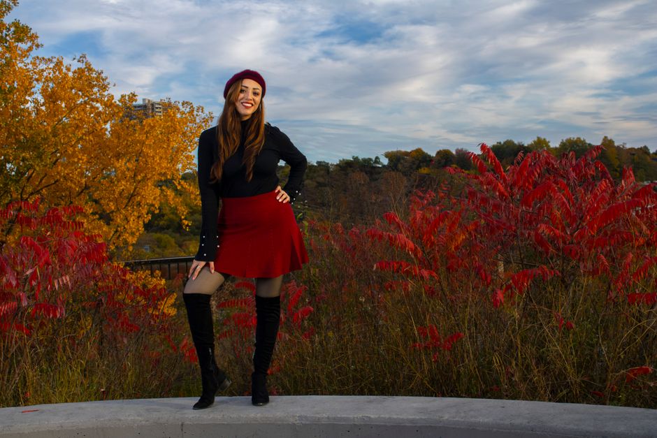 Woman posing in vibrant autumn colors with a red beret and skirt in Toronto, Canada