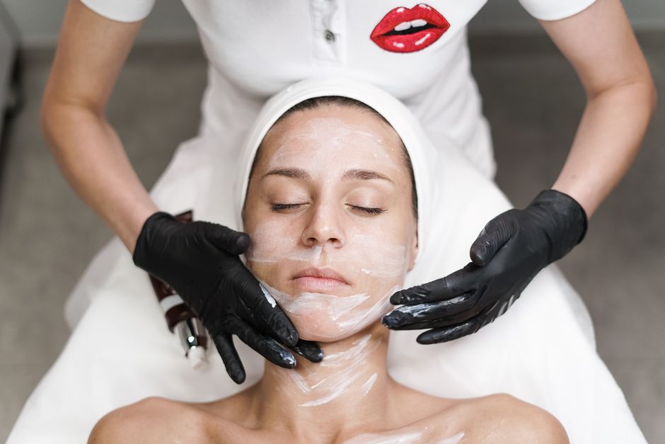 Woman receiving a facial treatment at spa, with beautician applying mask in a relaxing setting