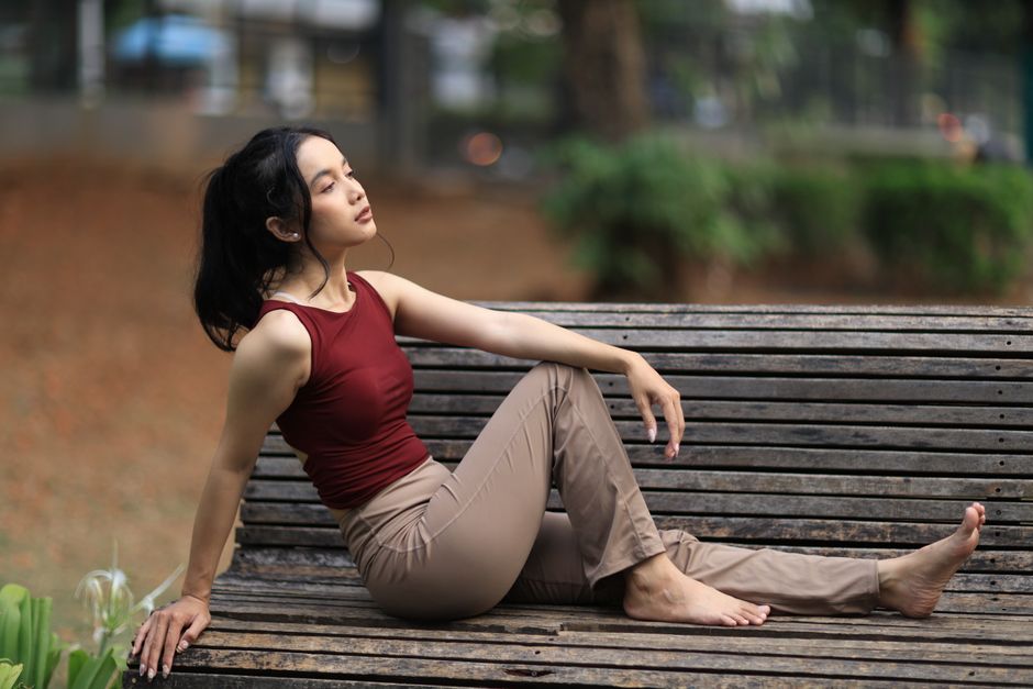 Young woman in casual attire relaxing on a park bench in Jakarta, Indonesia